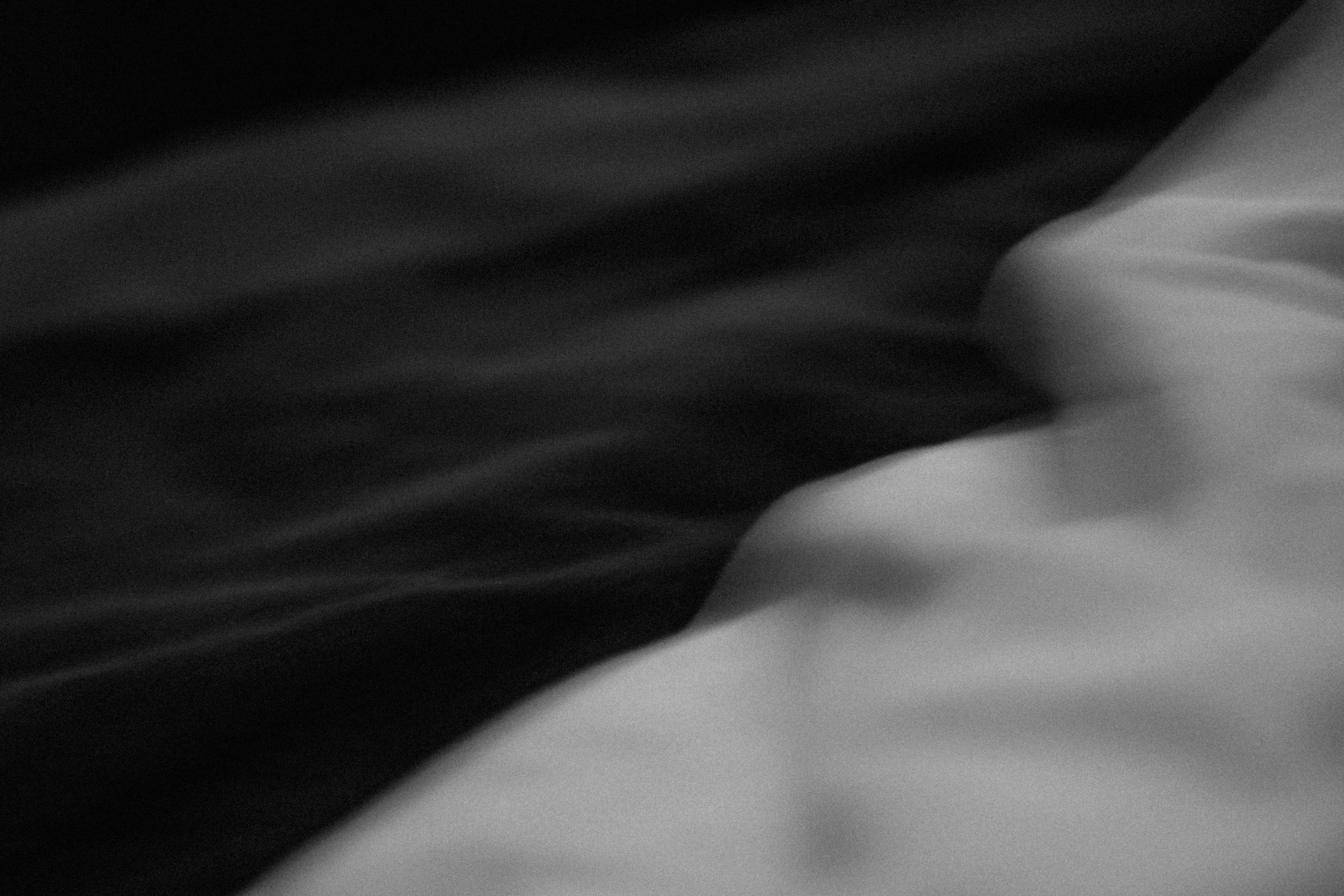 Rumpled bedsheets in low morning light